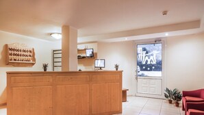 Zona de recepción con un escritorio de madera, un televisor y una puerta que ofrece vistas de las estrellas.