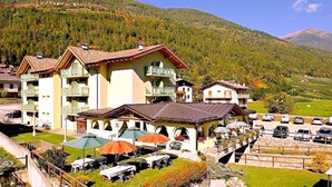 Un hotel con varias construcciones, mobiliario exterior y montañas al fondo.