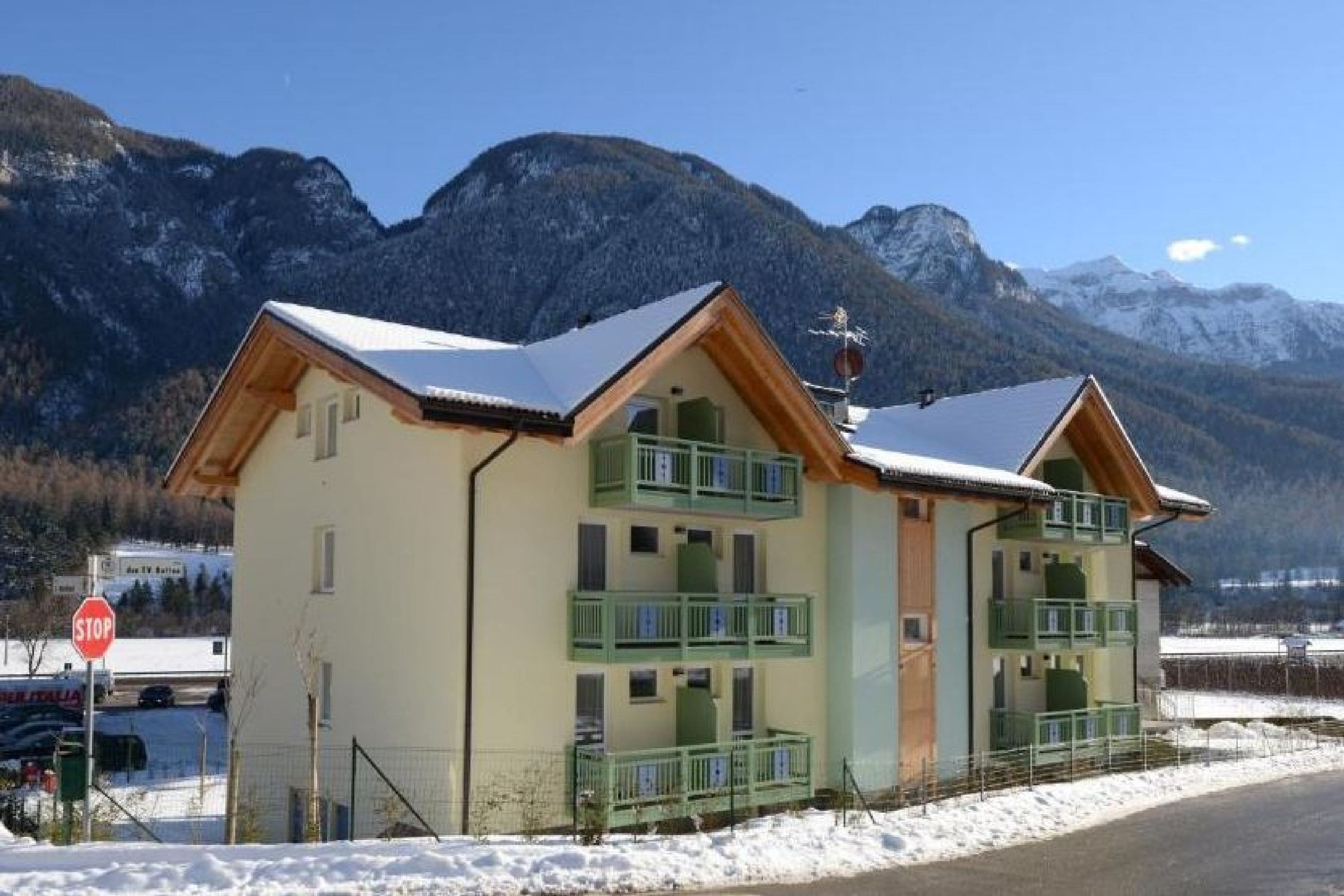 Un bâtiment à deux étages doté de balcons, d’un panneau de signalisation indiquant un arrêt obligatoire et d’un sol recouvert de neige.