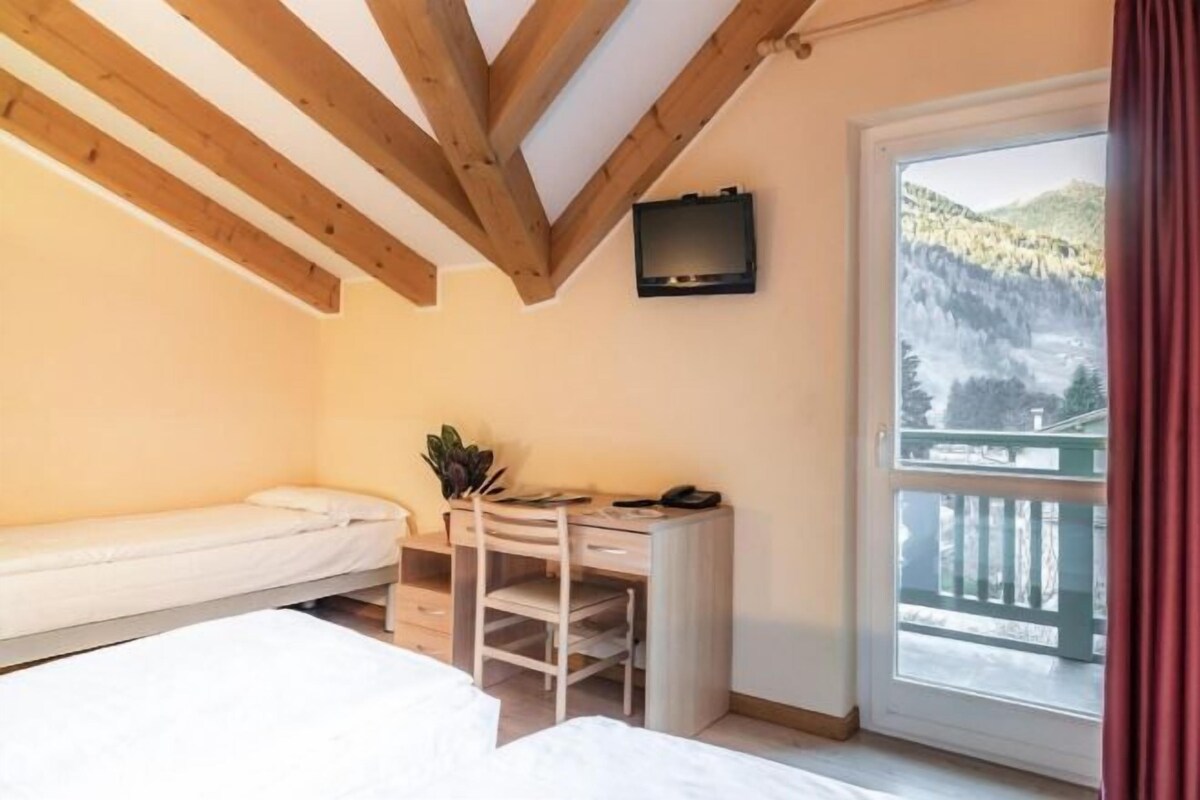 Un dormitorio con cama, escritorio y ventana con vistas a la montaña.