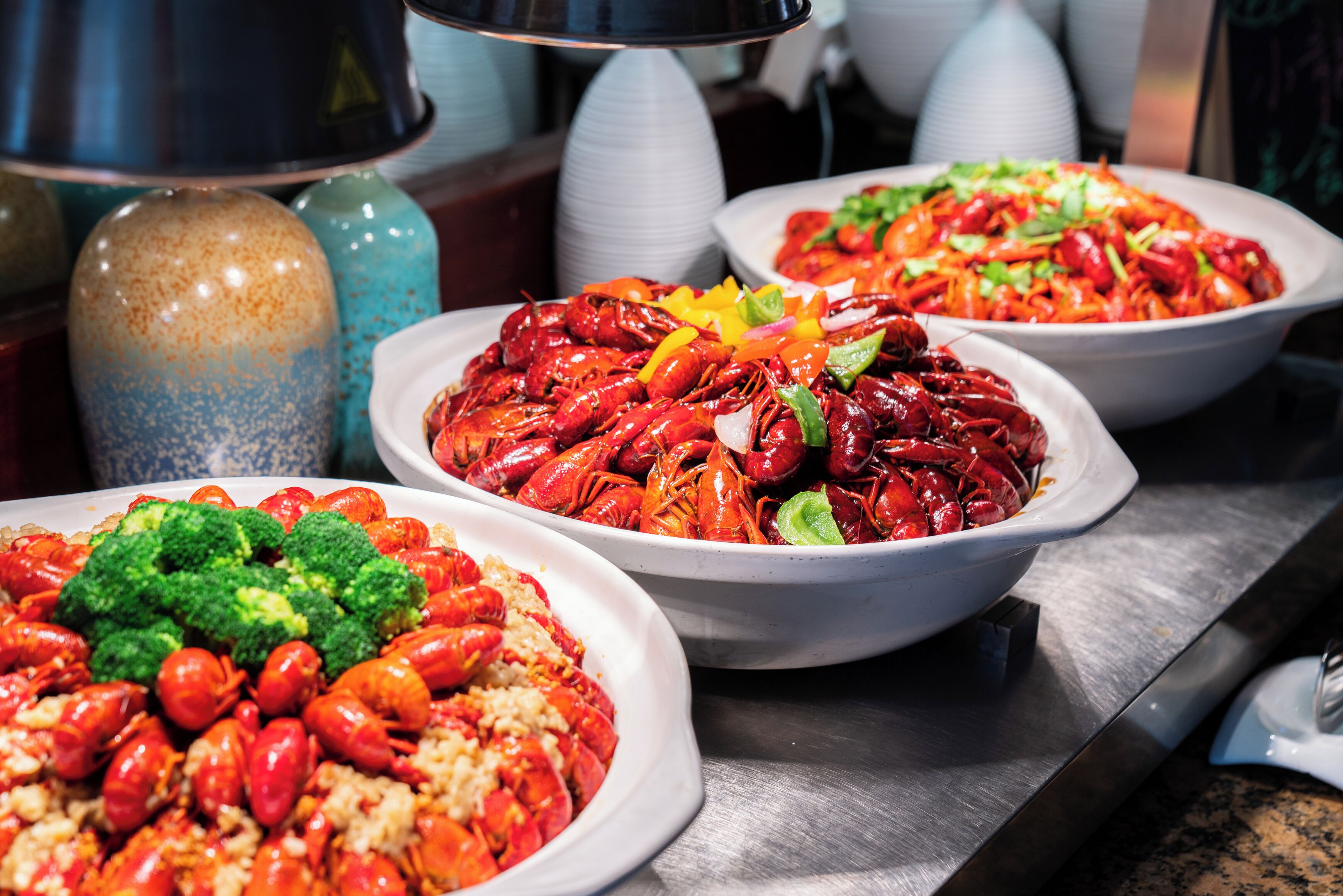 A buffet table with various dishes, including crawfish and rice.