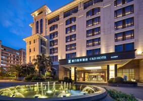 A hotel with a large fountain in front, multiple floors, and a well-lit entrance.