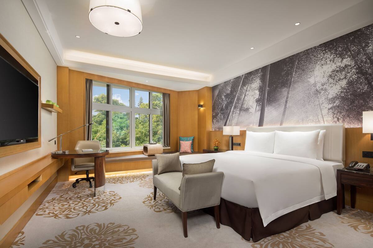 A spacious hotel room with a large bed, a desk, a chair, and a television.