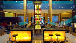 Un lobby moderno de hotel con una barra central, asientos y una escalera.