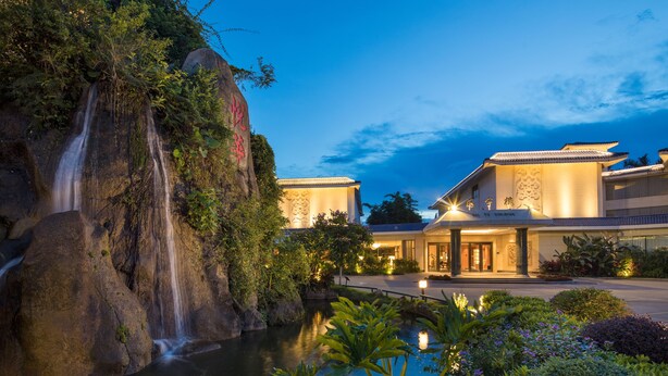 Un hotel con cascada, estanque y arquitectura tradicional.
