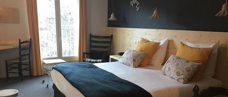 A hotel room with a bed, a desk, and a chair.