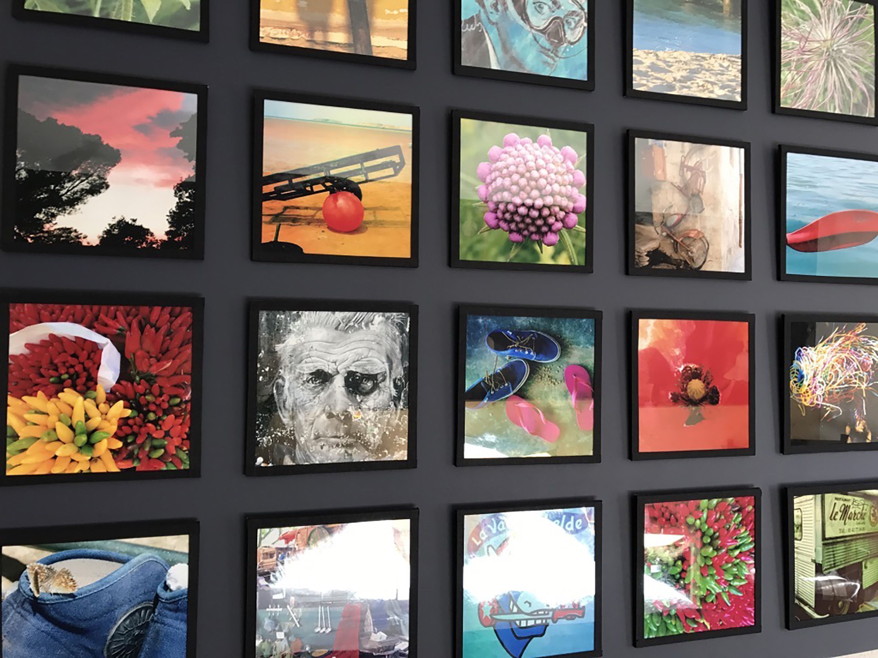 A wall with multiple framed artworks, including landscapes, flowers, and abstract designs.