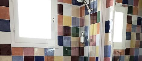Um banheiro com parede de azulejos em mosaico colorido, pia branca e banheira.