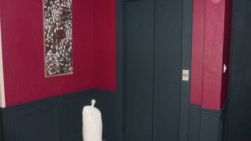 A hallway with a red wall, a door, and a white pillar.