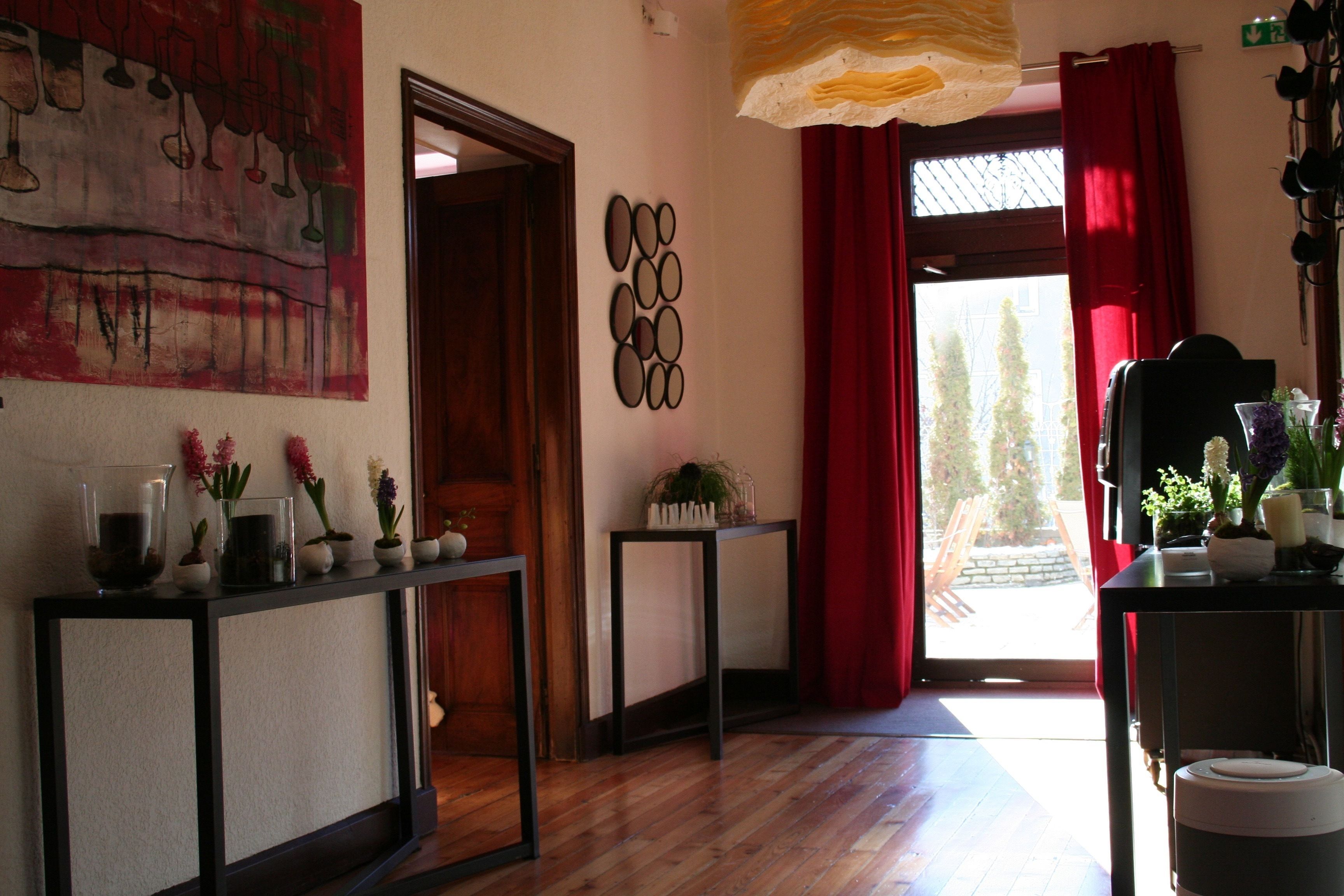 Une pièce dotée d’un plancher en bois, d’un rideau rouge, d’un mur orné d’un motif circulaire et d’une porte donnant sur un espace extérieur.