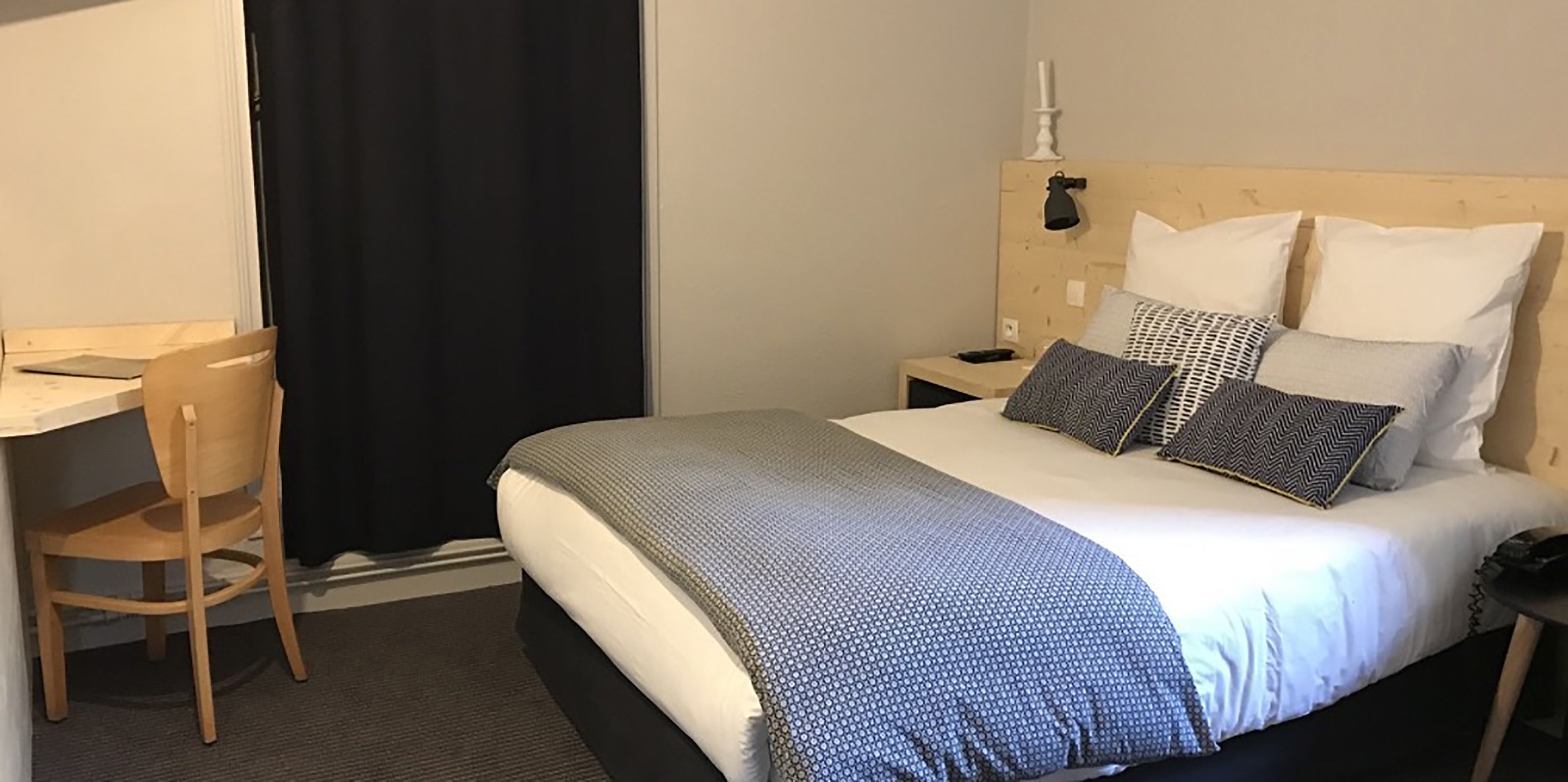 Ein Hotelzimmer mit Bett, Schreibtisch, Sessel und Nachttisch.