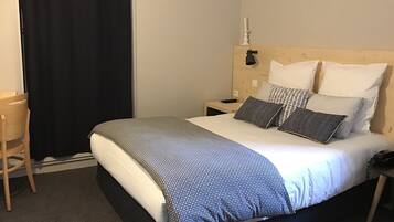 Ein Hotelzimmer mit Bett, Schreibtisch, Sessel und Nachttisch.