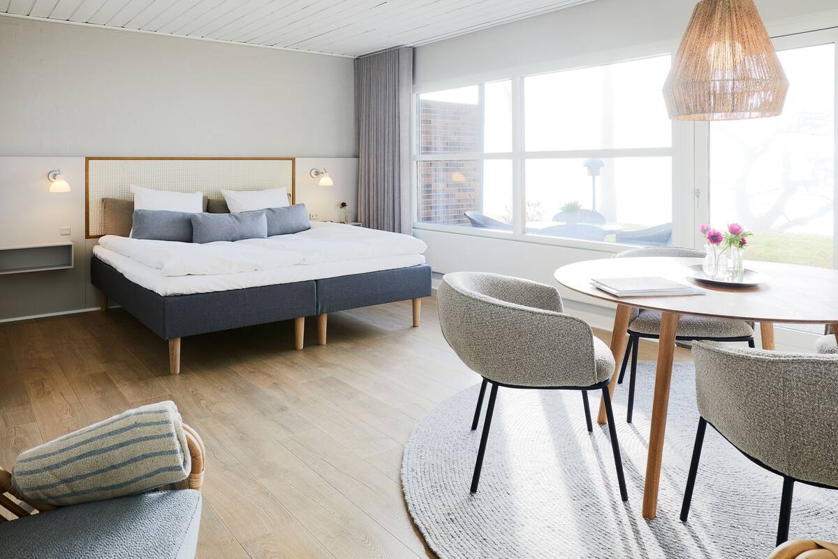A modern bedroom with a bed, bedside tables, a round dining table, and chairs.