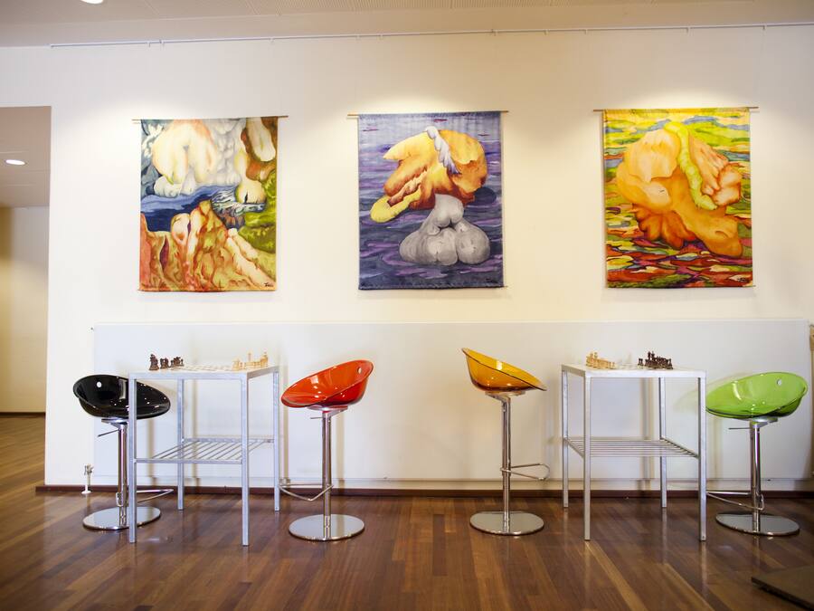 Uma galeria com três quadros e quatro banquetas.