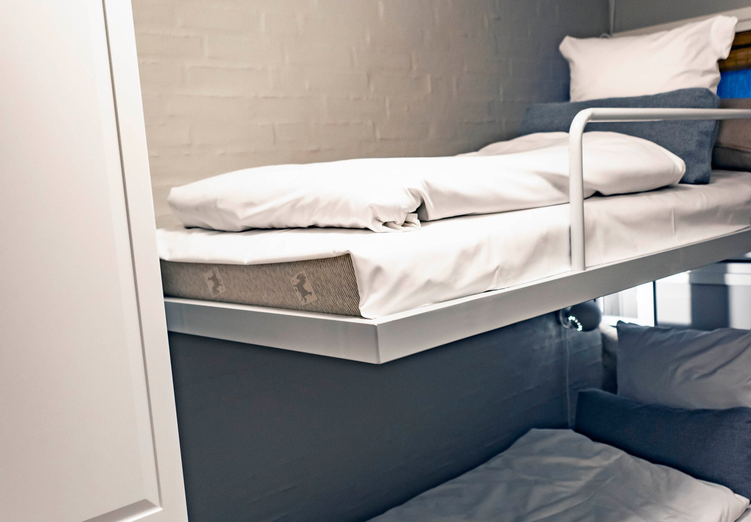 A bunk bed with white bedding and a grey lower bunk.