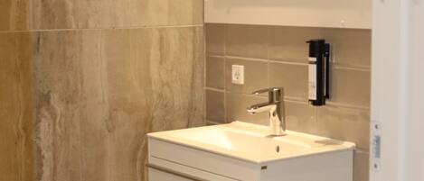 Une salle de bain moderne avec un lavabo blanc, des toilettes et un miroir au-dessus du lavabo.