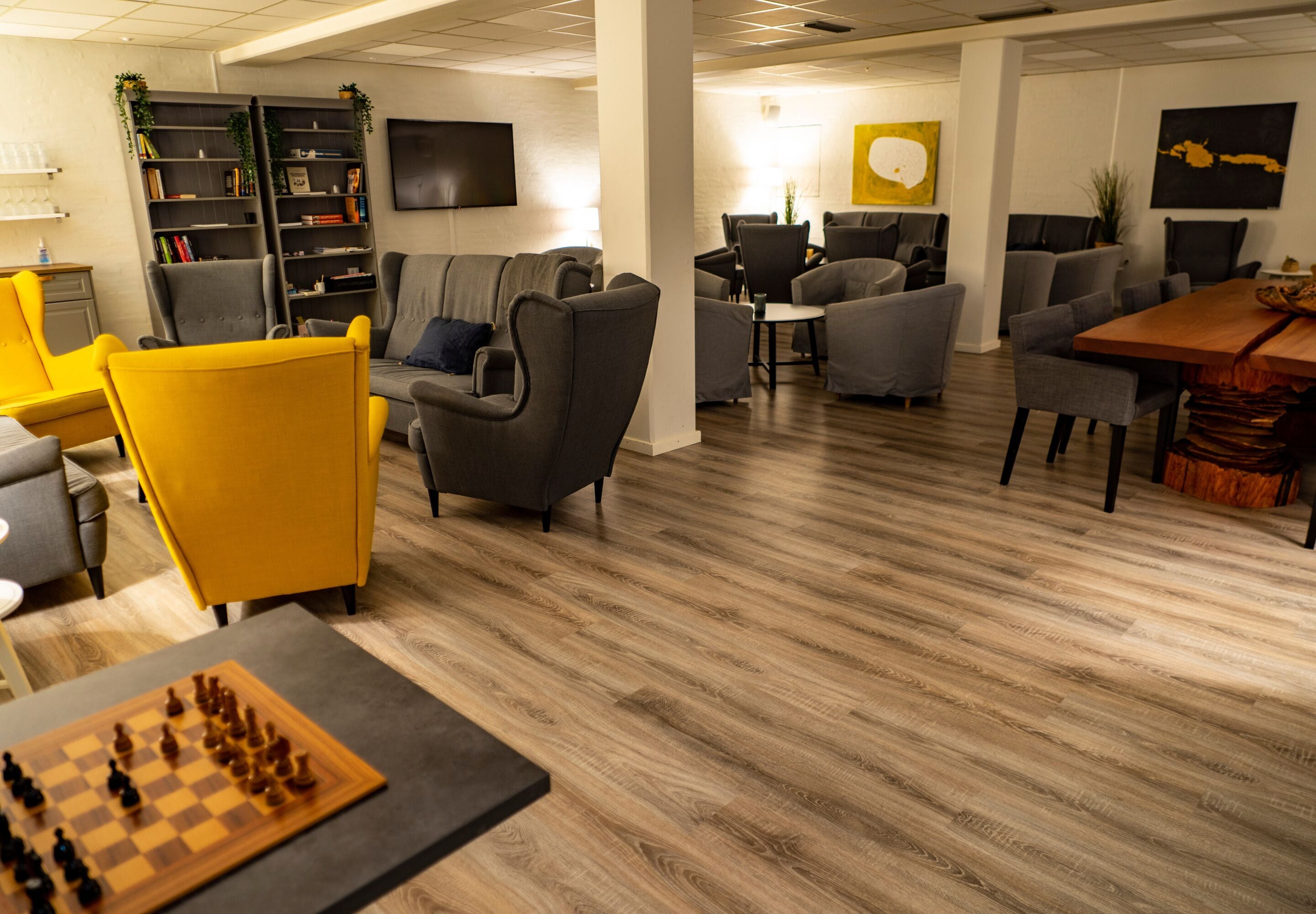 Een moderne lounge met banken, een schaakspel en een boekenkast.