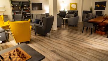 Een moderne lounge met banken, een schaakspel en een boekenkast.