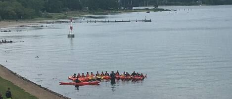 A group of people in a red canoe on a calm body of water, with a dock and trees in the background.