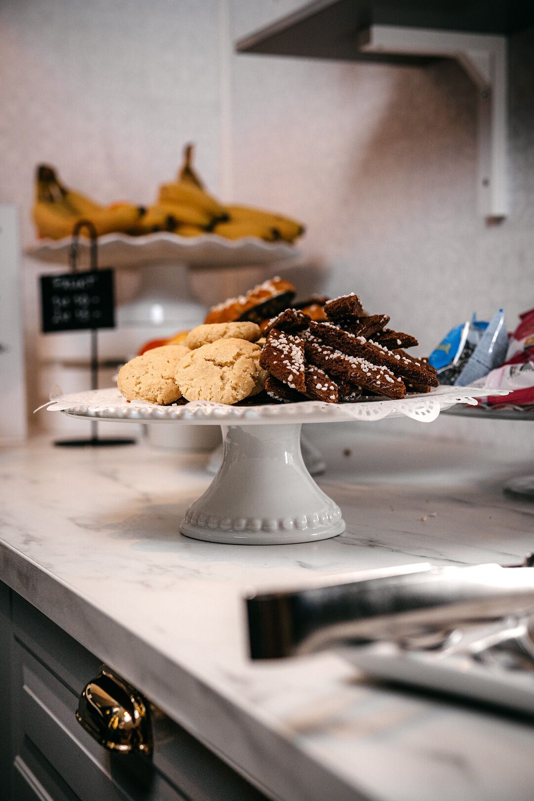 Una presentación de postres con galletas y brownies sobre un pedestal blanco.