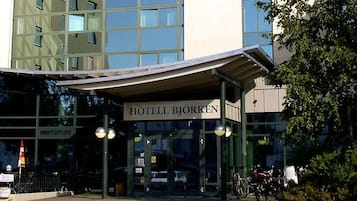 L’extérieur de l’hôtel Björken se distingue par sa façade moderne en verre, son entrée abritée et son espace de stationnement pour vélos.