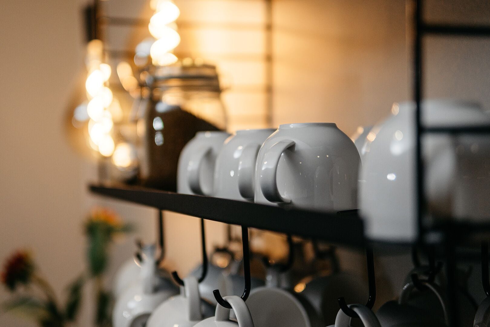 A shelf with white ceramic mugs and teapots.