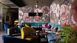 A modern living room with a blue sofa, a yellow armchair, and a black coffee table. - Design-Hotel JAMS (Munich)