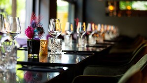A long dining table with multiple wine glasses and a decorative vase. - Design-Hotel JAMS (Munich)