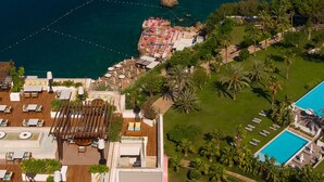 Vista aérea de un resort con piscina, áreas de descanso y una terraza de comedor.