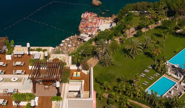 An aerial view of a resort with a pool, lounge areas, and a dining terrace.