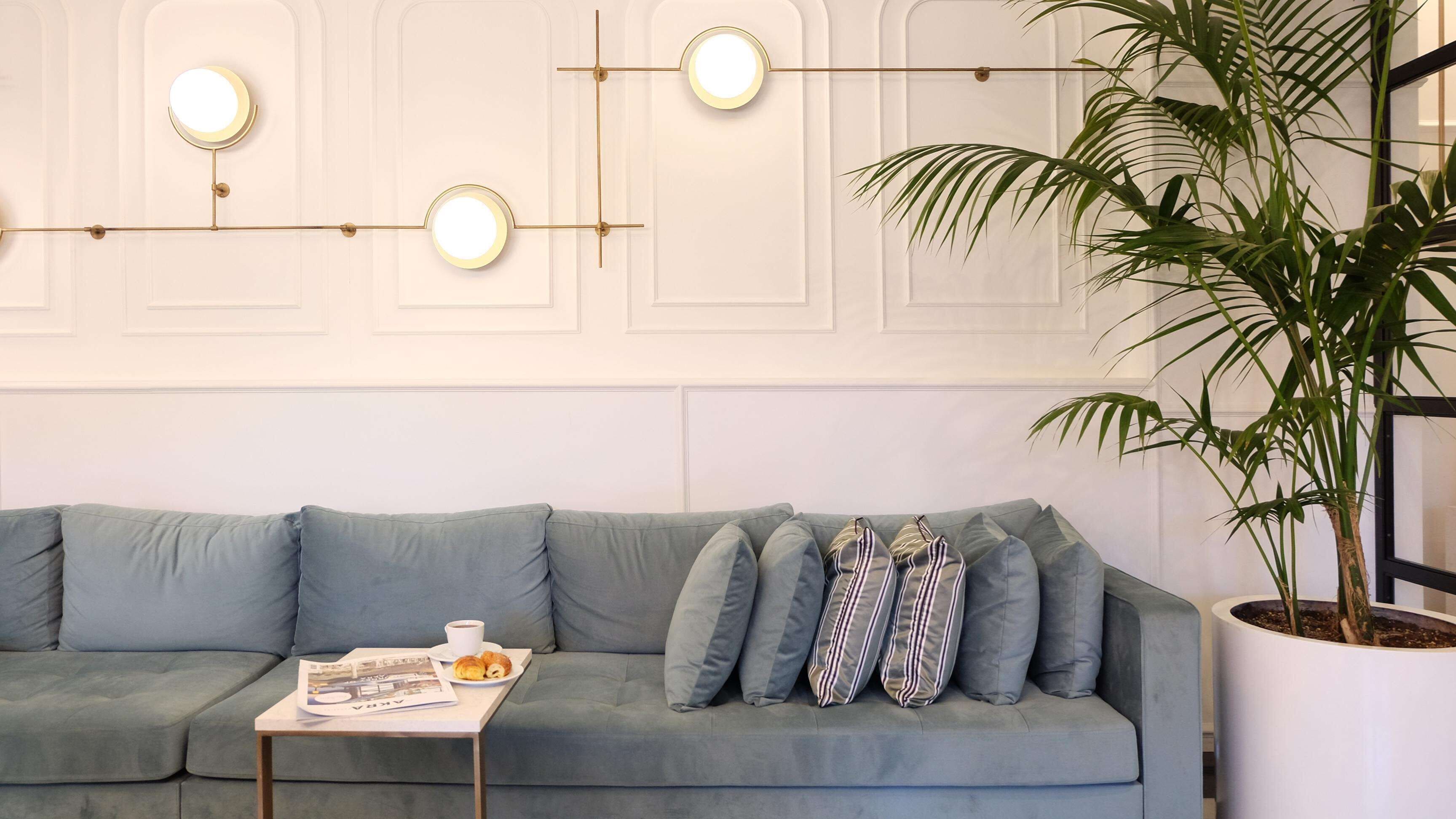 A modern living room with a grey sofa, a coffee table with a newspaper, and a potted plant.