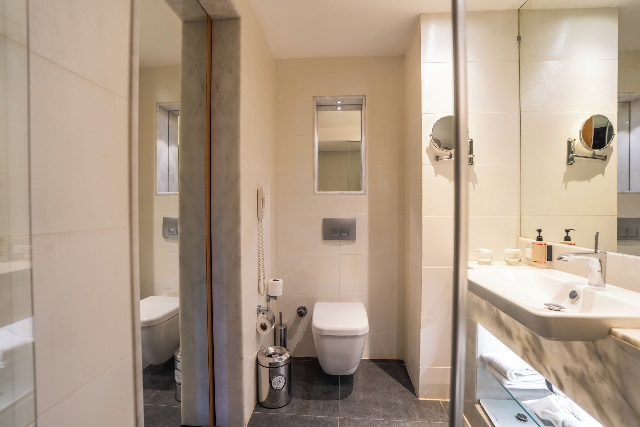 A modern bathroom with a toilet, bidet, and a large sink with a mirror.