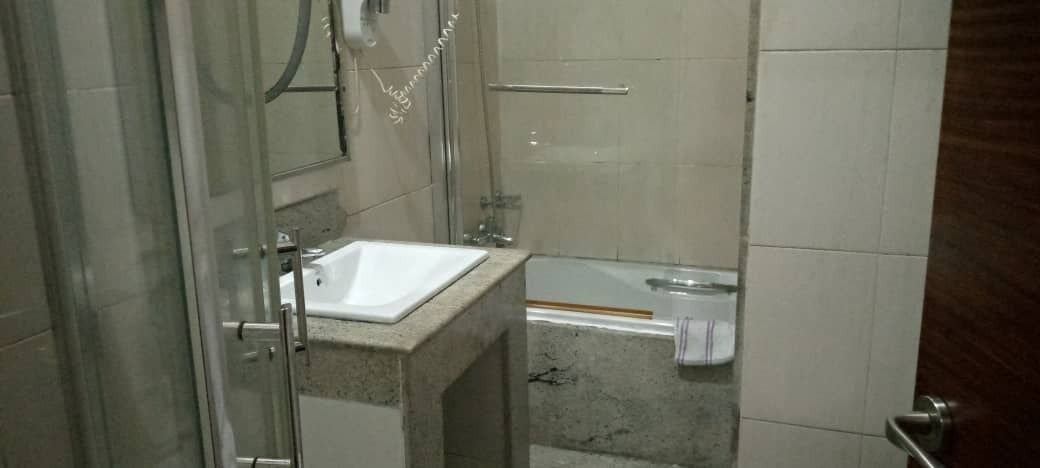 A bathroom with a glass shower enclosure, a white sink, and a bathtub.