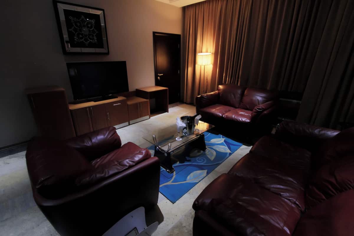 Een woonkamer met leren banken, een salontafel, een flatscreen televisie en een lamp.
