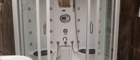 Una ducha a pie con puertas de cristal y dos cabezales de ducha manuales.