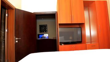 A hotel room with a bed, a television, a desk with a computer, and a wardrobe.