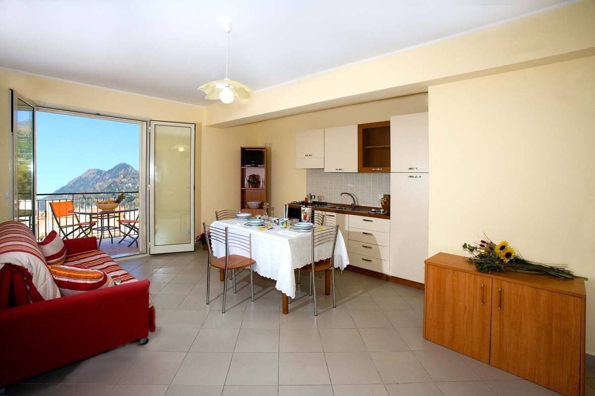 Un ambiente compatto con angolo ristoro, angolo cottura e balcone con vista sulle montagne.