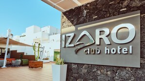 A hotel sign with the name "IZARO CLUB HOTEL" and a stone wall backdrop. - Gloria Izaro Club Hotel (Tías)