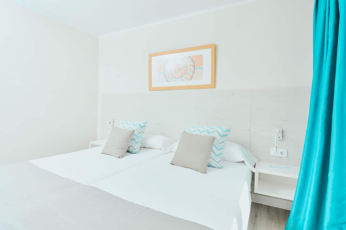 A hotel room with a bed, nightstand, and a wall-mounted picture.