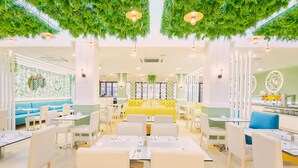 A modern restaurant with white and yellow seating, green hanging plants, and a bright interior. - Gloria Izaro Club Hotel (Tías)