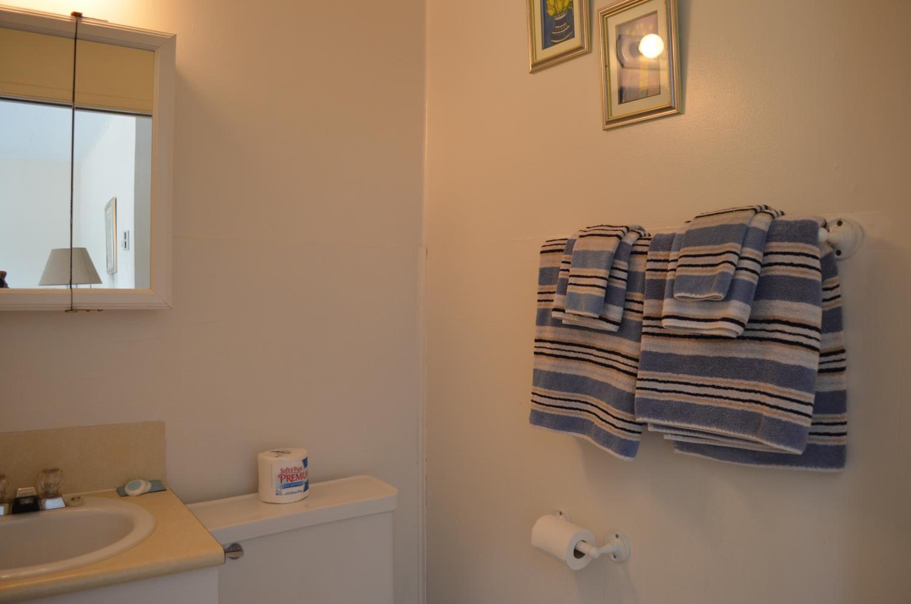 A bathroom with a toilet, a sink, and two towels hanging on the wall.