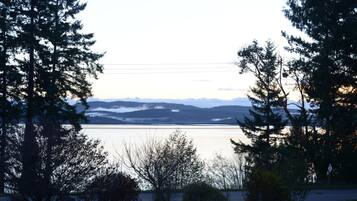 Um lago com montanhas ao fundo, rodeado por árvores.