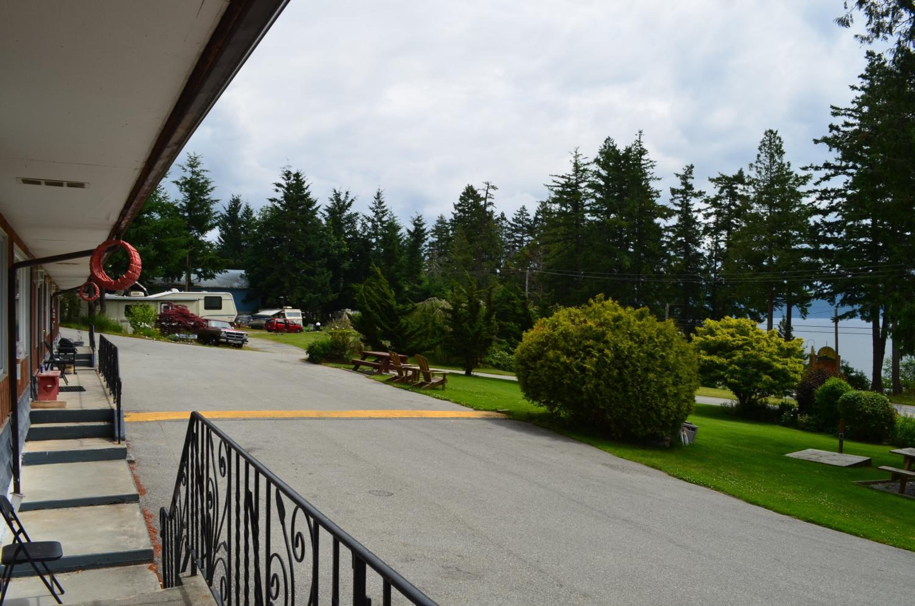 A street view with a building on the left, a picnic area, and a grassy area with trees.