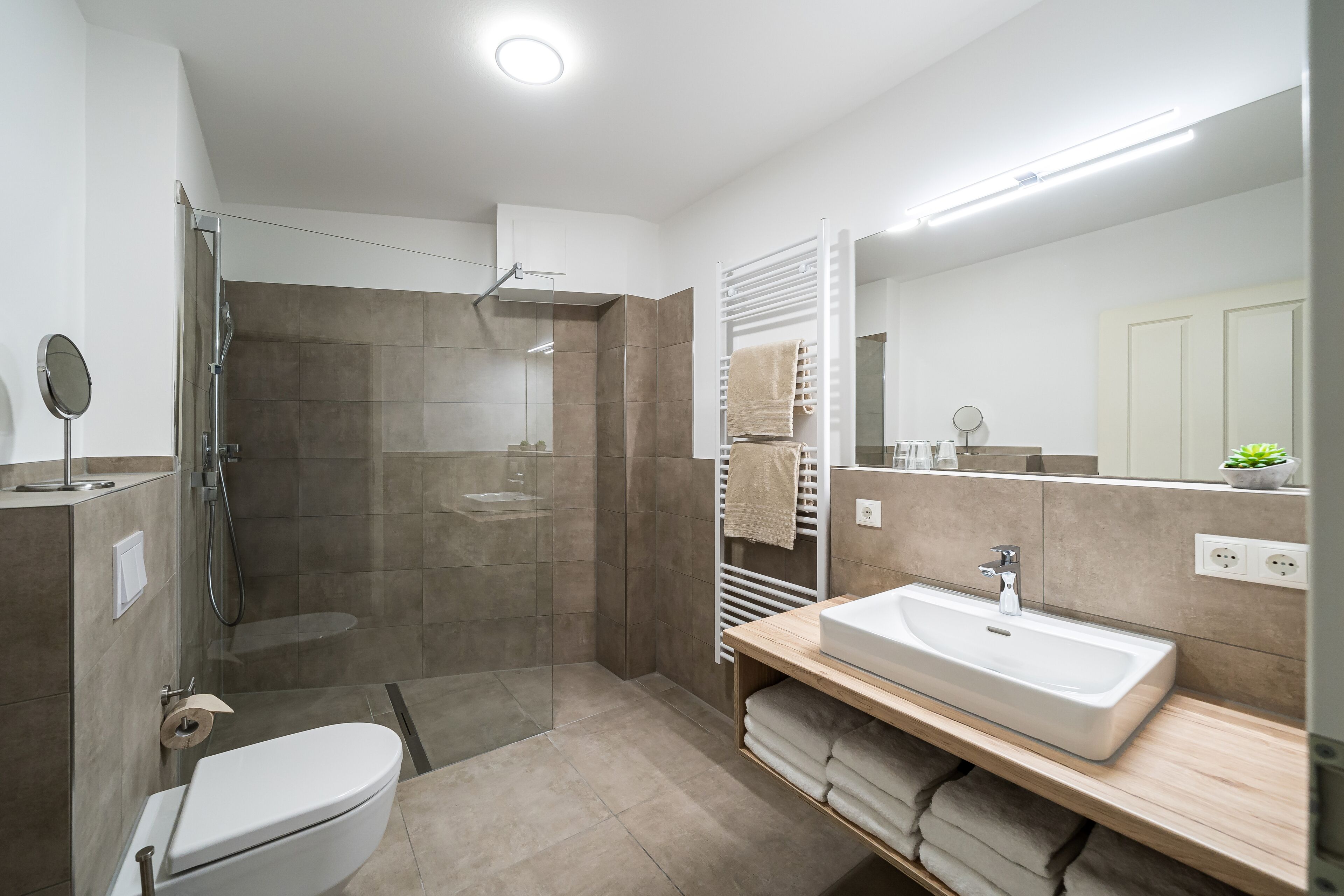 A modern bathroom with a shower, toilet, sink, and a mirror.
