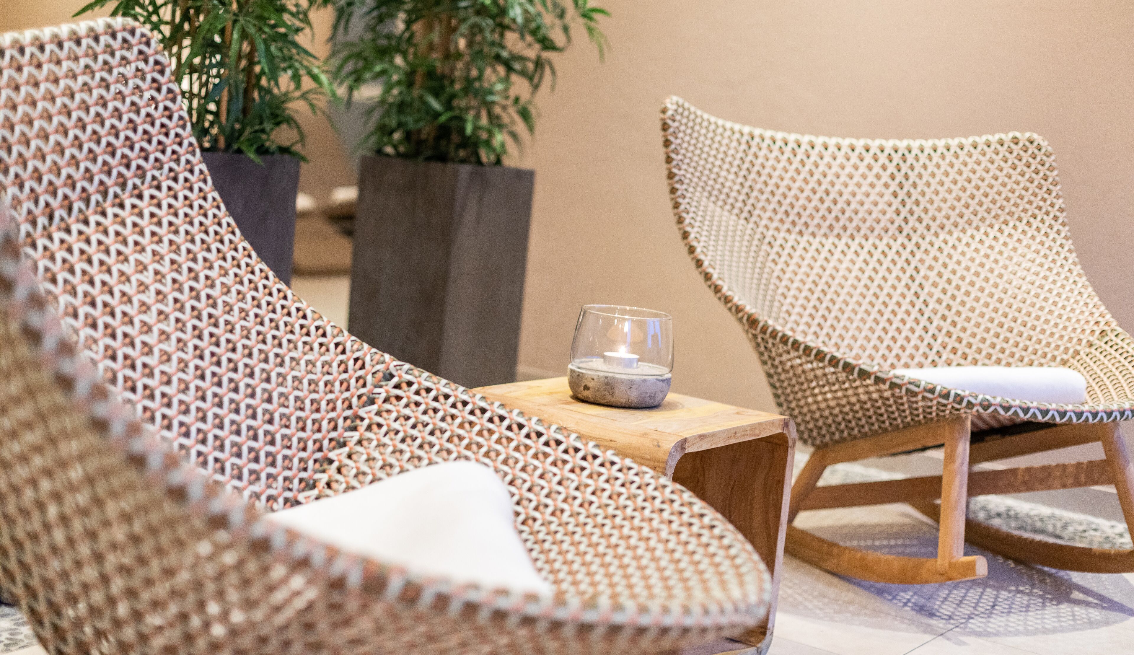 Sillones de mimbre con cojines, una mesita y una vela.