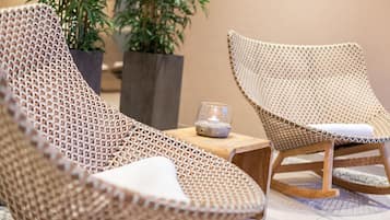 Sillones de mimbre con cojines, una mesita y una vela.
