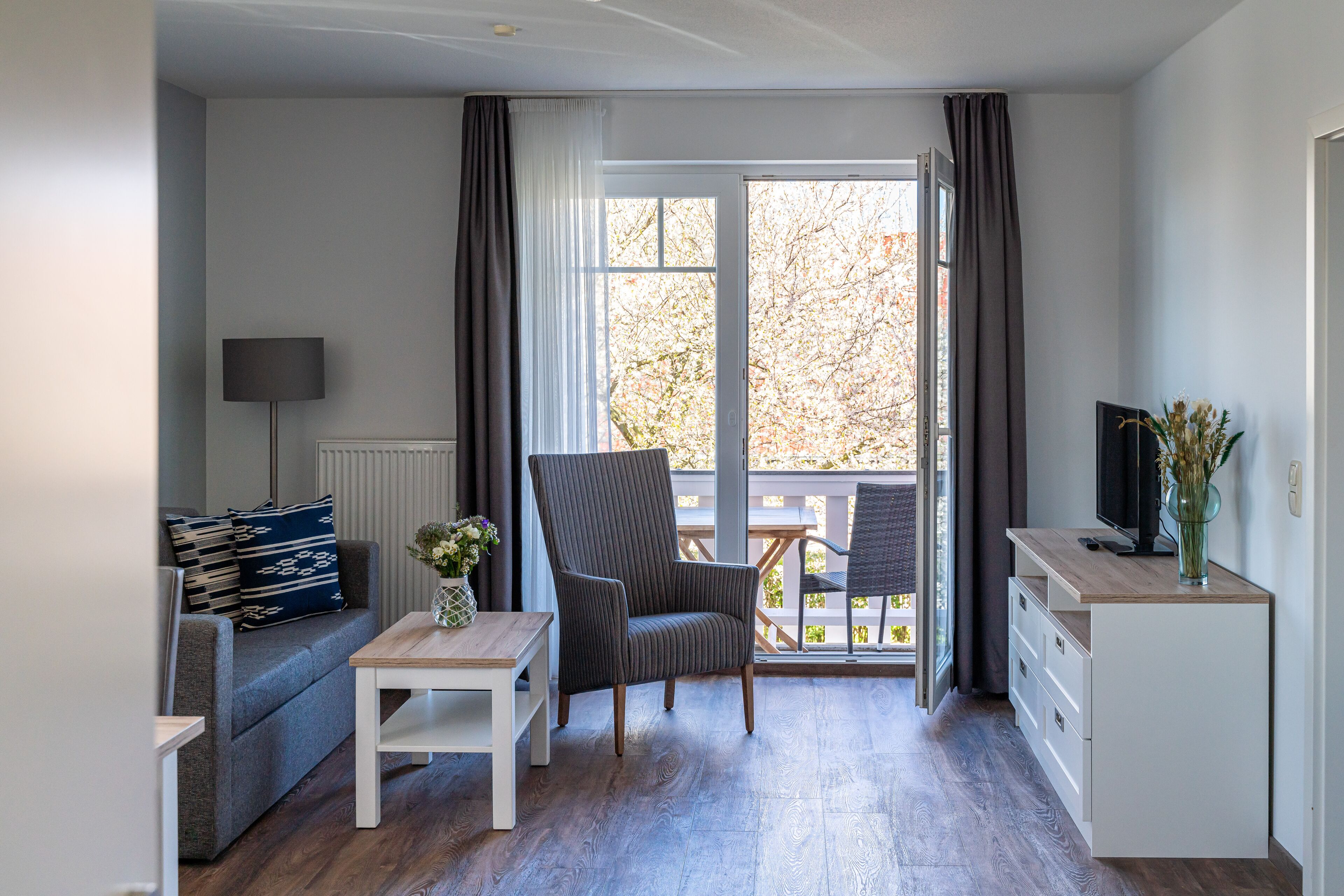 A compact living space with a sofa, a small table, a chair, a TV, and a cabinet.