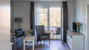 A compact living space with a sofa, a small table, a chair, a TV, and a cabinet.