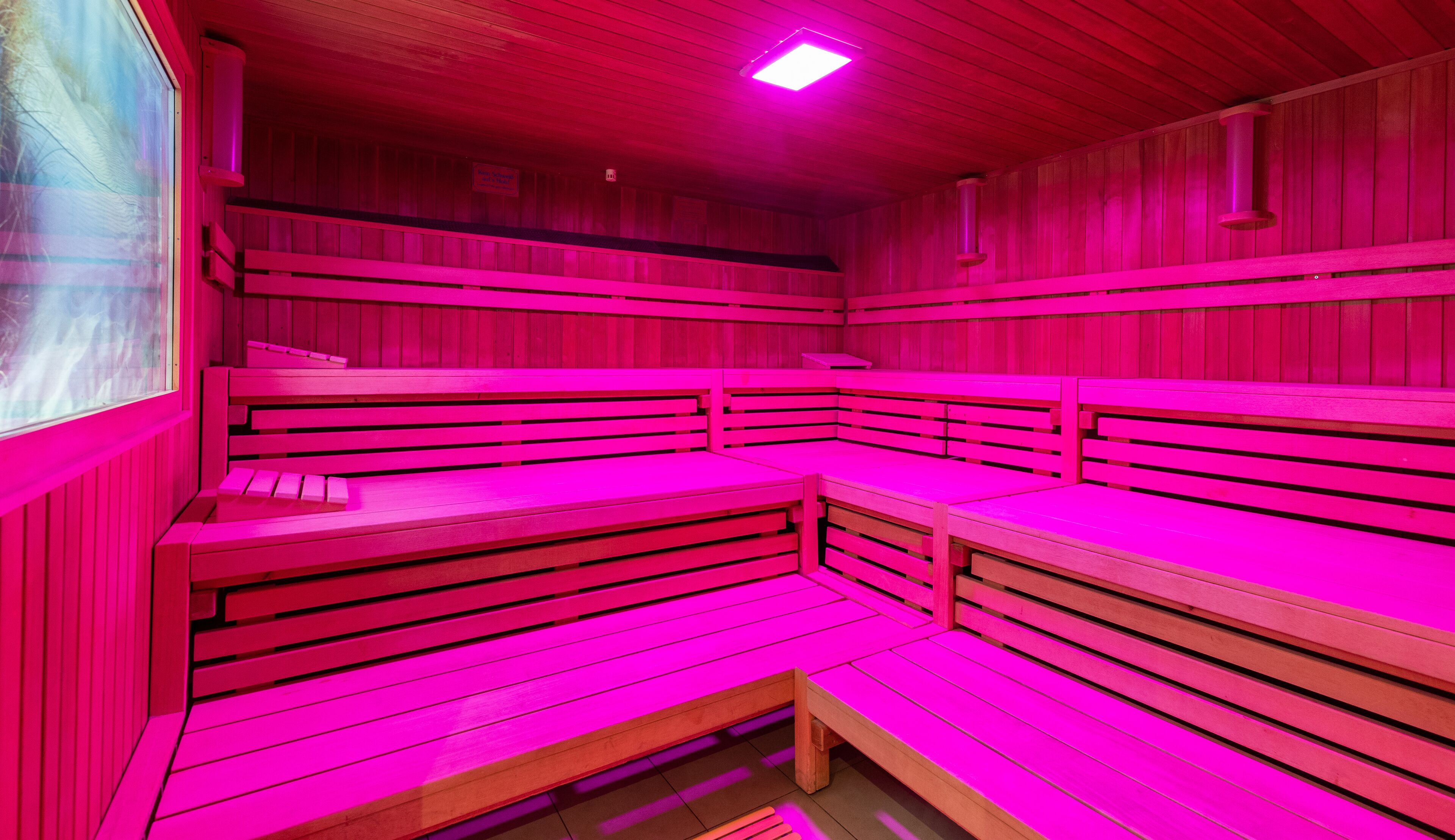 A sauna with multiple benches and a wooden ceiling.