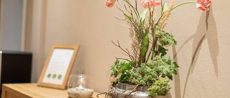 A vase with pink flowers and green foliage on a wooden table.
